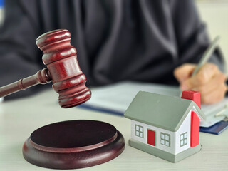Legal proceedings involving a judge gavel and a model house during a real estate dispute concept