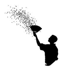 Silhouette of person holding fan spreading confetti.