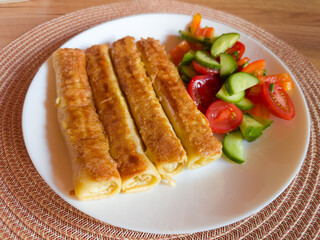 Fried pancakes are stuffed and rolled up served on dish