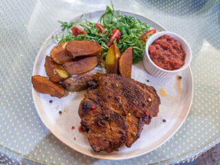Fried pork steak served with baked potato and fresh vegetables