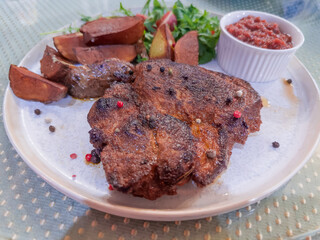 Fried pork steak served with baked potato and fresh vegetables