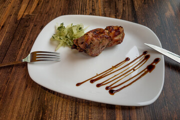 Grilled shashlik pieces on white plate on wooden table