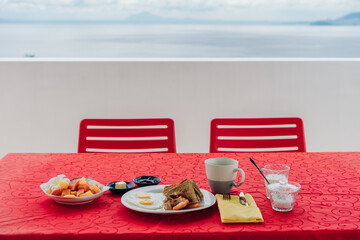 breakfast on a red tablecloth on the background of the ocean