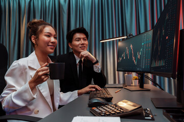 Smiling businesswoman in white suit looking on dynamic stock exchange statistic on pc screens...