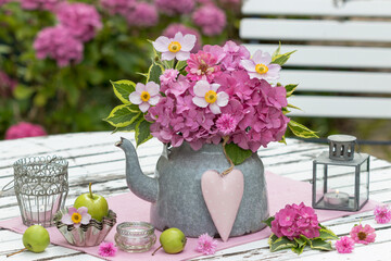 Garten-Arrangement mit  Blumenstrauß mit pink Hortensienblüten und Herbst-Anemonen und vintage Laternen