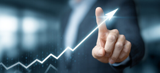 Businessman touching a glowing upward arrow graph symbolizing business growth, success, and financial progress

