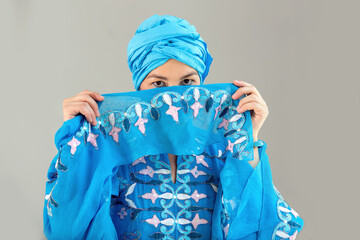 Woman covers her face. Young woman in oriental blue dress. Eastern dance.