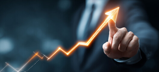 Businessman touching a glowing upward arrow graph symbolizing business growth, success, and financial progress

