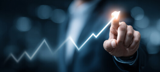 Businessman touching a glowing upward arrow graph symbolizing business growth, success, and financial progress

