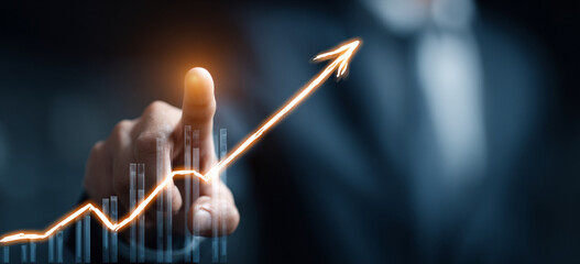 Businessman touching a glowing upward arrow graph symbolizing business growth, success, and financial progress

