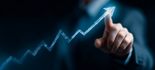 Businessman touching a glowing upward arrow graph symbolizing business growth, success, and financial progress

