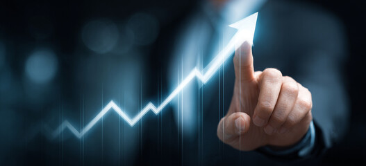 Businessman touching a glowing upward arrow graph symbolizing business growth, success, and financial progress

