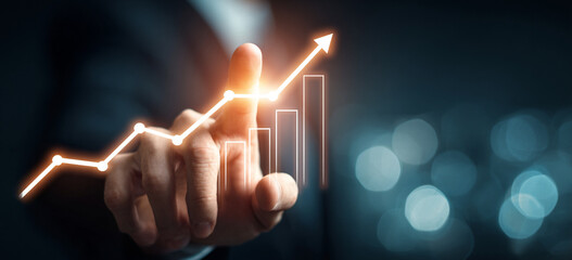 Businessman touching a glowing upward arrow graph symbolizing business growth, success, and financial progress

