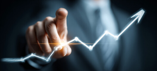 Businessman touching a glowing upward arrow graph symbolizing business growth, success, and financial progress

