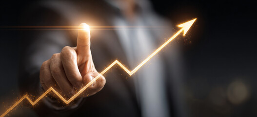 Businessman touching a glowing upward arrow graph symbolizing business growth, success, and financial progress

