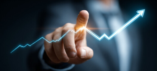 Businessman touching a glowing upward arrow graph symbolizing business growth, success, and financial progress

