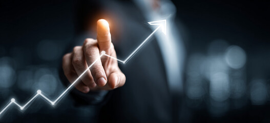 Businessman touching a glowing upward arrow graph symbolizing business growth, success, and financial progress

