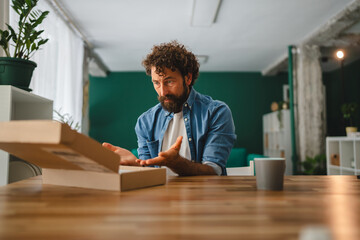 Confused man opening empty delivery box at home