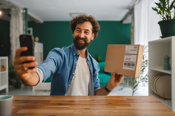 Small business owner taking self portrait with parcel for social media