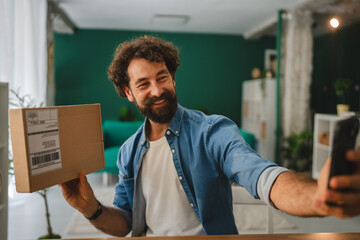 Entrepreneur taking self portrait with parcel at home office