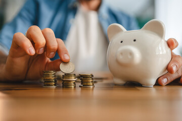 Man stacking coins and holding piggy bank: saving money concept
