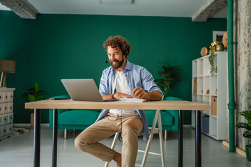 Freelancer working from home having video call using laptop and headset
