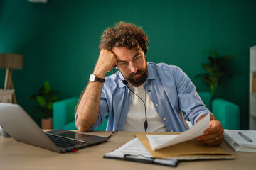 Tired businessman working from home having a headache and reading documents