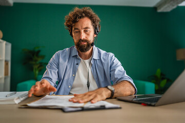 Focused entrepreneur managing documents during online meeting at home office