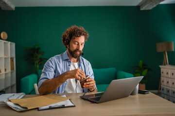 Man with headset drinking from a flask while working from home