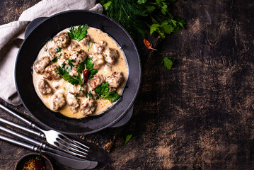 Meatballs in sour cream sauce in a frying pan