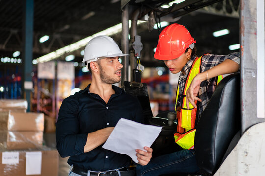 Warehouse supervisor and female forklift operator reviewing documents. Concept of teamwork, training, and logistics management in an industrial environment
