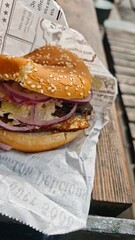 Close-up of a fish burger with pickled red onion and coleslaw served in a sesame bun. Street food...