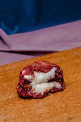 Close-up of a delicious red velvet cookie with a creamy white filling, cut in half to reveal the...