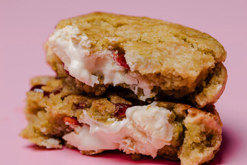 A stack of two delicious cookies with a creamy filling oozing out against a vibrant pink backdrop. Sweet, indulgent treats perfect for any occasion.