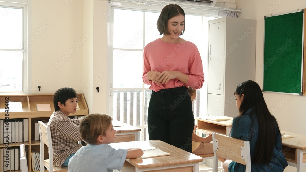 Aufkleber caucasian teacher walking and check student homework at classroom while diverse children doing class