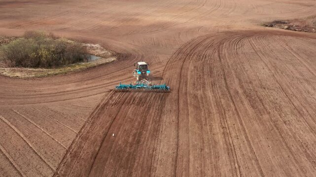 A tractor with a grain seeder is working in the field