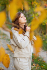 young woman stands on autumn path and folds hands praying to god, concept religion and lifestyle