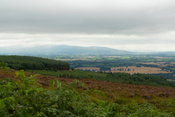 Obraz premium Breathtaking panorama of rolling hills and lush valleys under an overcast sky in the heart of the countryside