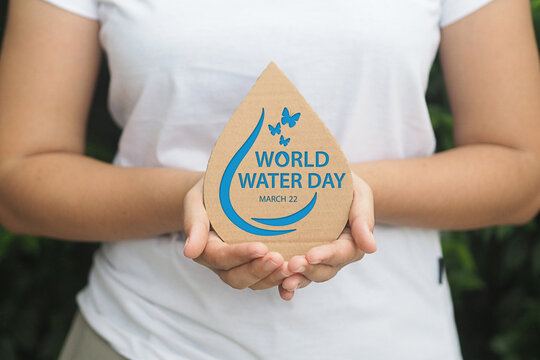 Woman hand holding paper cut water drop on green background. Save water. World Water Day concept.