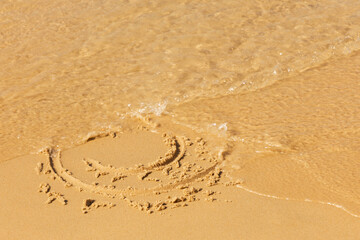A painted smiley face on the beach sand