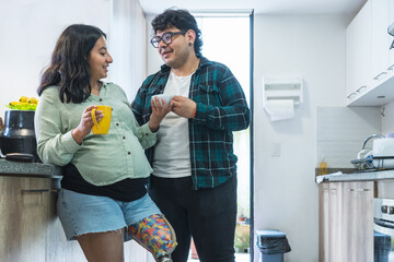 Pregnant woman with prosthetic leg and husband enjoying coffee in kitchen