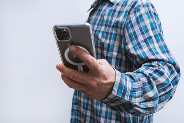 Man in a plaid shirt holding smartphone with blank screen on light background. Portable mobile technology concept.