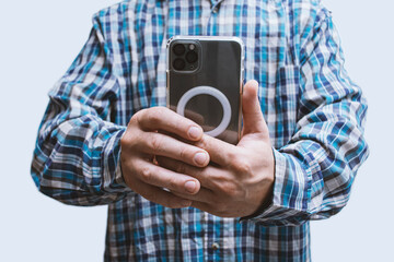 Close-up of a man in a plaid shirt taking a photo with a modern smartphone in vertical mode. Mobile photography, tech usage and content creation.