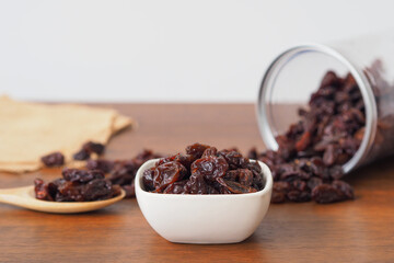 Raisins in bowl on wooden table background. Raisins in wooden spoon. Raisins spilling out of jar. Dry raisins.