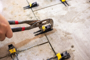 A technician removes leveling clips from freshly laid tiles with pliers, demonstrating the final stages of installation
