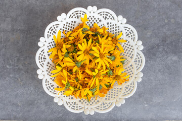 Top view, white vase filled with bright yellow Jerusalem artichoke flowers, a useful plant being dried for making tea
