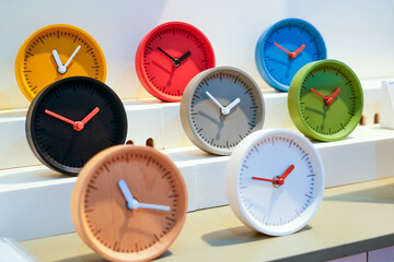 Round variety of modern clocks in vibrant colors are arranged neatly on a shelf in a design store,...