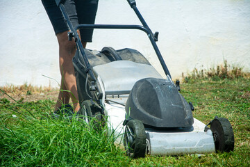 Unknown man mows the grass in the garden