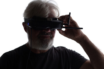 silhouette of bearded elderly man operating FPV drone in googles on his head, studio shot of man and modern technologies