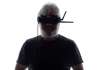 silhouette of bearded elderly man operating FPV drone in googles on his head, studio shot of man and modern technologies